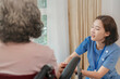 © ultramansk - An elderly woman in a wheelchair shares a conversation with a caring healthcare professional in an outdoor setting. The scene highlights support, healthcare, and emotional well being in a peaceful.