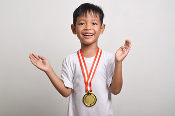 Asian boy with a gold medal isolated on a white background with a surprised facial expression. trophy for the first place