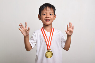 Happy and excited asian boy holding a first place gold medal isolated on a white background. The boy celebrating his victory