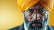 © JoxyAimages - Close-up portrait of a bearded man wearing a yellow turban and glasses, exuding confidence and determination against a warm orange background.