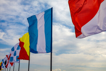 A row of flags with a blue stripe and yellow and red stripes. The flags are on a pole and are in the sky