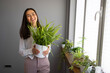 © Dragana Gordic - Woman Smiling While Holding Potted Plant in Bright Room