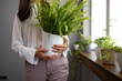 © Dragana Gordic - Woman Holding Indoor Fern Plant in Bright Modern Setting