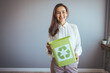 © Dragana Gordic - Smiling Woman Holding a Recycling Bin in a Bright Room