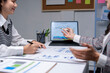 © Wasana - Two businesswomen analyzing financial summary report on tablet computer screen