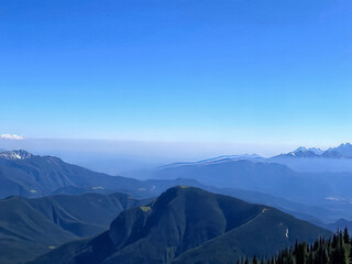 Wall Mural - The sky is blue and the mountains are covered in snow. The mountains are very tall and the snow is very white