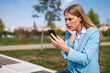 © inesbazdar - Shocked and worried  businesswoman looking at her mobile phone while sitting on the bench outdoor.
