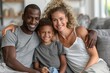 © Robert Anto - A happy family of three sitting close together on a sofa, with the parents embracing their child, creating a warm and loving family moment in a cozy home setting.