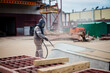 © Anoo - A worker sandblasts a large metal structure to remove rust at an industrial plant during a clear day