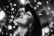 © vasyan_23 - Joyful woman in sparkling hat celebrating amidst falling confetti in monochrome
