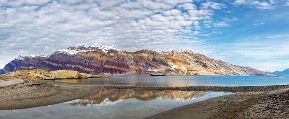 Wall Mural - segelsallskapet panorama with reflection. a tail ship is anchored in the clear blue fjord, with the 