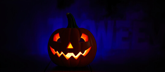 Wall Mural - glowing carved pumpkin sits on a table with a blue hazy background