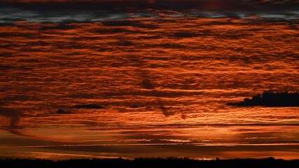 Wall Mural - time lapse sunset of spectacular moving orange and gray clouds above a distant horizon. powerline ne
