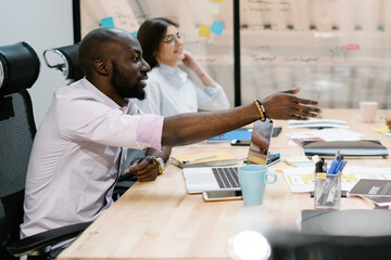 Diversity group of confident male and female experts of proud ceo collaborating together in office, crew sitting at desk with laptops and talking about innovation in world of modern technology