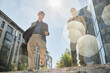 © Seventyfour - Low angle shot of two smiling male colleagues of different ethnic background walking down stairs enjoying talk and sunny day on way to work in city street, boleh effect