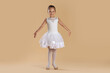 © New Africa - Little ballerina practicing dance moves on beige background
