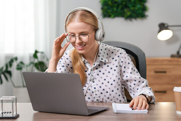 Wall Mural - Interpreter in headphones working with laptop at table indoors