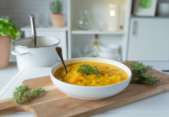 Delicious homemade pumpkin soup with potatoes, corn and yellow peppers. Served ready to eat on a plate on kitchen counter background