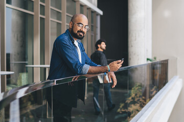 Contemporary smiling man with phone on balcony