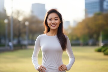 Poster - Portrait of a blissful asian woman in her 20s showing off a lightweight base layer on vibrant city park