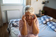 © Geber86 - Senior woman having headache on bed at home