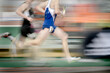 © Lane Erickson - Running a Relay Race on Track Holding Baton Team Effort and Competition
