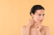 © New Africa - Beautiful woman peeling off face mask on beige background. Space for text