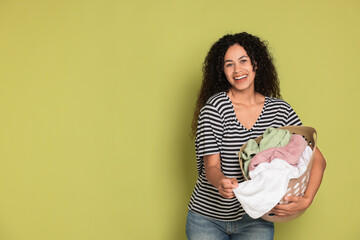 Poster - Happy woman with basket full of laundry on olive background, space for text