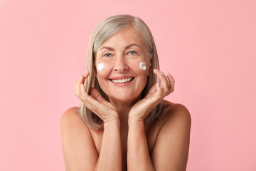 Poster - Senior woman with face cream on pink background