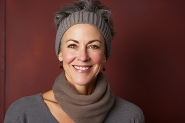 Poster - Portrait of a grinning woman in her 50s donning a warm wool beanie in pastel brown background