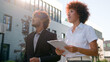 © Yuliia - Indian man Arabian businessman investor client and African American woman realtor saleswoman businesswoman talking walking in city looking at modern urban buildings business discussing investment