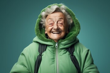 Wall Mural - Portrait of a jovial elderly woman in her 90s wearing a windproof softshell in soft green background