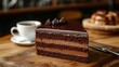 © esp2k - A slice of chocolate cake with chocolate frosting on a wooden cutting board