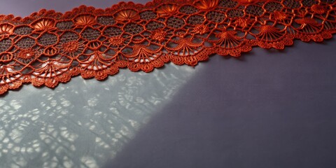 Poster - Intricate red lace casting a shadow on a gray surface.