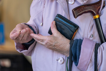 pensioner counting money into her purse. close up of hands. poor pensioner concept.