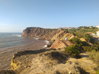 Coastal cliff view of rough waves crashing against the rocks in the afternoon sunlight at a scenic seaside location