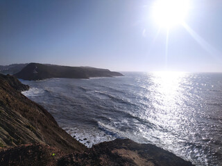 Coastal cliff view of rough waves crashing against the rocks in the afternoon sunlight at a scenic seaside location