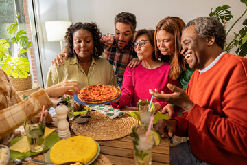 Happy diverse family enjoying pizza and drinks at home