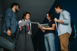 © qunica.com - A group of university students engage in a lively discussion with their professor in a hallway. They appear focused and collaborative, exchanging ideas and reviewing documents together.