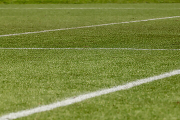 Football field with synthetic grass, with an angle below, highlighting the green of the lawn and some white lines.