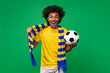 © wpadington - Portrait of euphoric screaming soccer supporter man wearing yellow-blue scarf posing with a ball in hand over green background cheering up for his favorite team