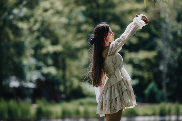 A carefree young woman is captured twirling joyfully in a sunlit park, wearing a light floral dress, showcasing a moment of freedom and happiness.