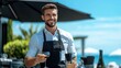 © Pinklife - A cheerful waiter in a black apron and white shirt serves wine at an outdoor cafe, showcasing hospitality and a pleasant atmosphere on a sunny day.
