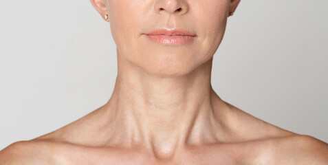 Skin care. Half face portrait of mature woman with wrinkled neck, grey background, crop