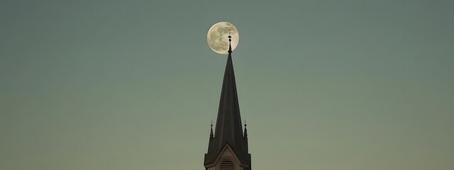 A moon is seen in the sky behind an old church bell tower