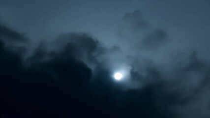 Wall Mural - Small moon peeks through dark storm clouds, creating mystery in the night sky with eerie blue hues and silver moonlight. Perfect for stormy evenings