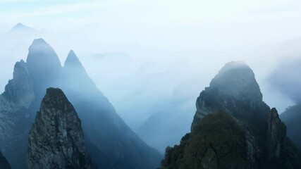 Wall Mural - Majestic mountain peaks are shrouded in a mystical fog, creating an ethereal and serene landscape that evokes a sense of tranquility and awe
