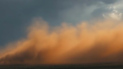 Wall Mural - Dark storm clouds are gathering over a vast empty landscape with low hills in the distance, creating a dramatic and moody atmosphere