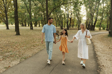 Joyful family stroll through a scenic park on a sunny day.