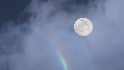Wall Mural - Bright full moon shines in the night sky, casting a soft glow on dark clouds, illuminating the atmosphere with a vibrant rainbow